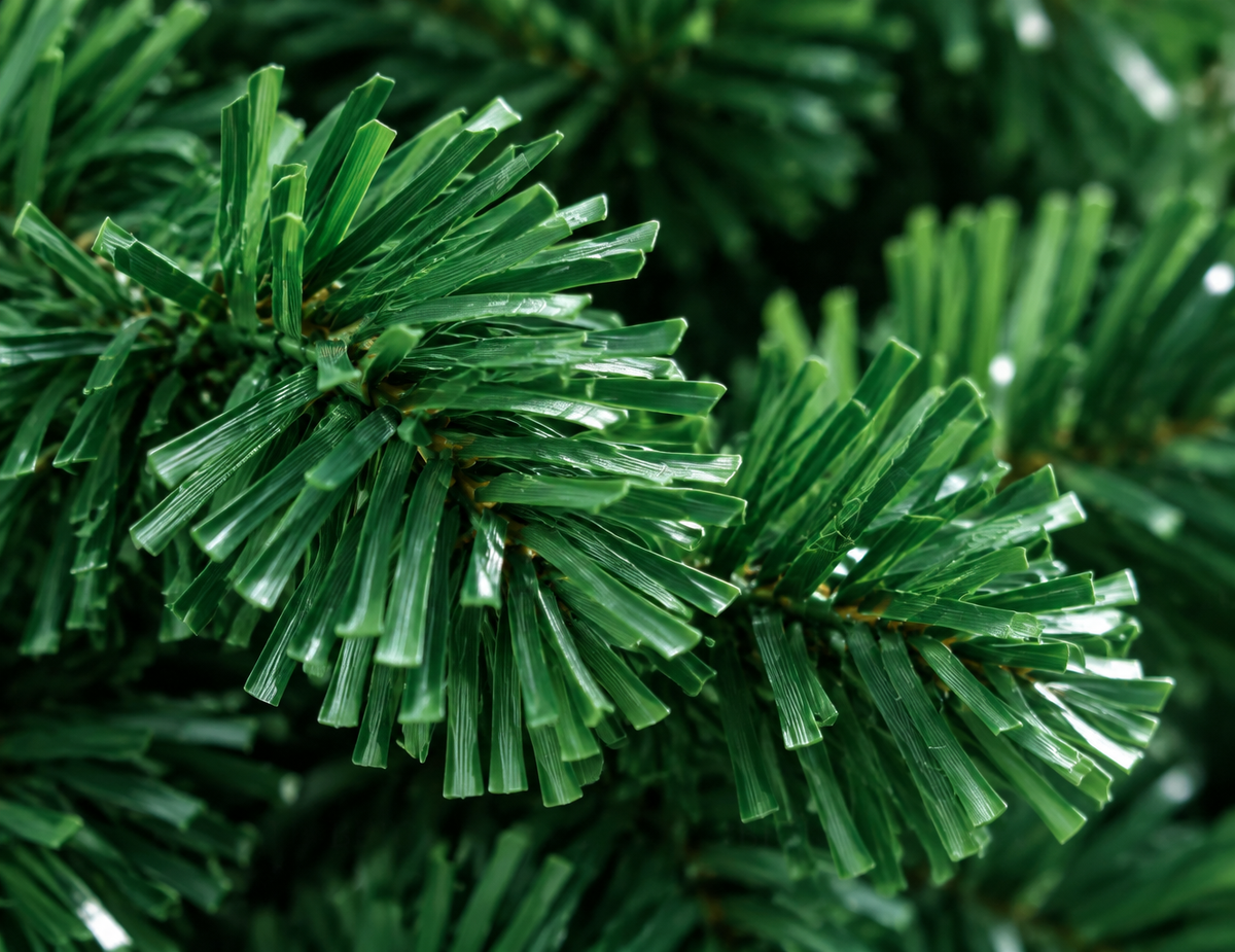 A very tight macro photograph of the artificial tree's green PVC branch material matching reference